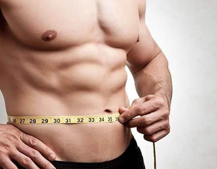 Picture of a man using a tape measure to show how his abdomen is flatter after a male tummy tuck with liposuction in Costa Rica.