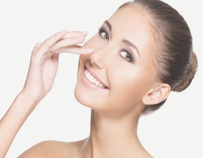 Picture of a woman with her finger on her nose showing her happiness with her nose surgery procedure in Costa Rica.